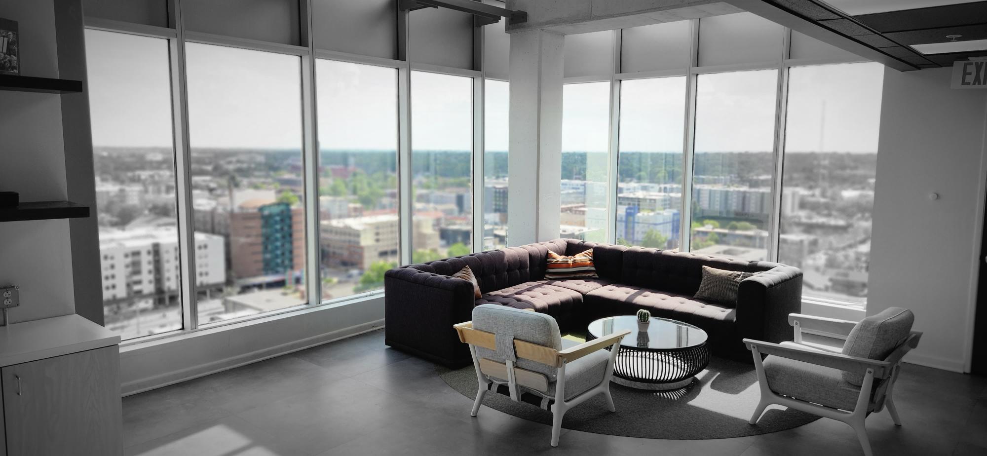 spacious community room with couch and tall windows overlooking city